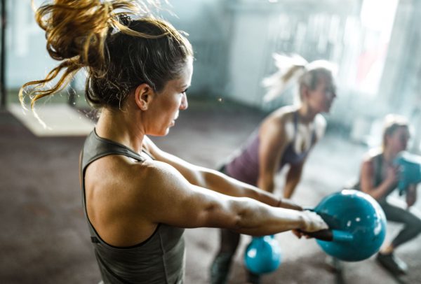 a woman swinging a kettlebell in a group fitness class